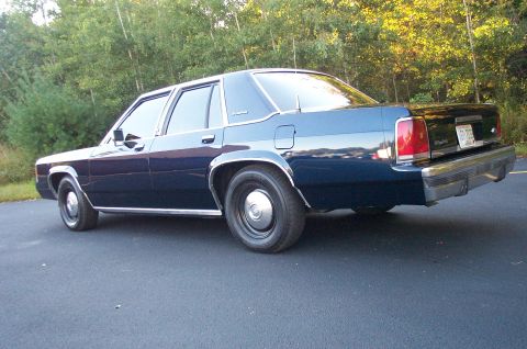 1991 Ford LTD Crown Victoria - This sedan has a chrome bumper and a license plate that reads 'FHP 105'.