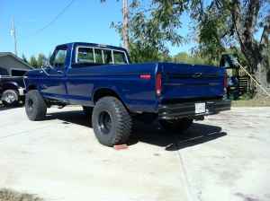 1995 Ford Bronco - Rear view of a lifted blue pickup truck with oversized tires.