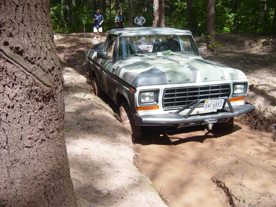 Ford F-Series pickup truck with camouflage paint stuck in mud, license plate KWC-6532