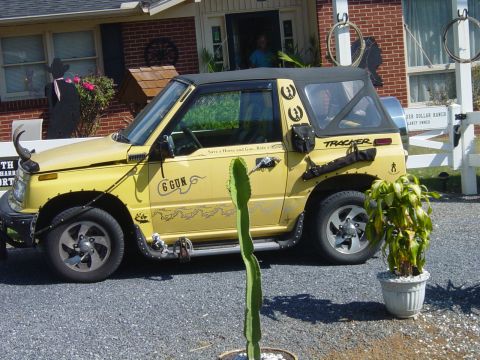 1979 Ford Bronco - A yellow Suzuki Samurai is parked in front of a house with western-themed decorations.
