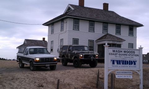 1979 Ford Bronco - Two SUVs are parked in front of the Wash Woods Coast Guard Station.