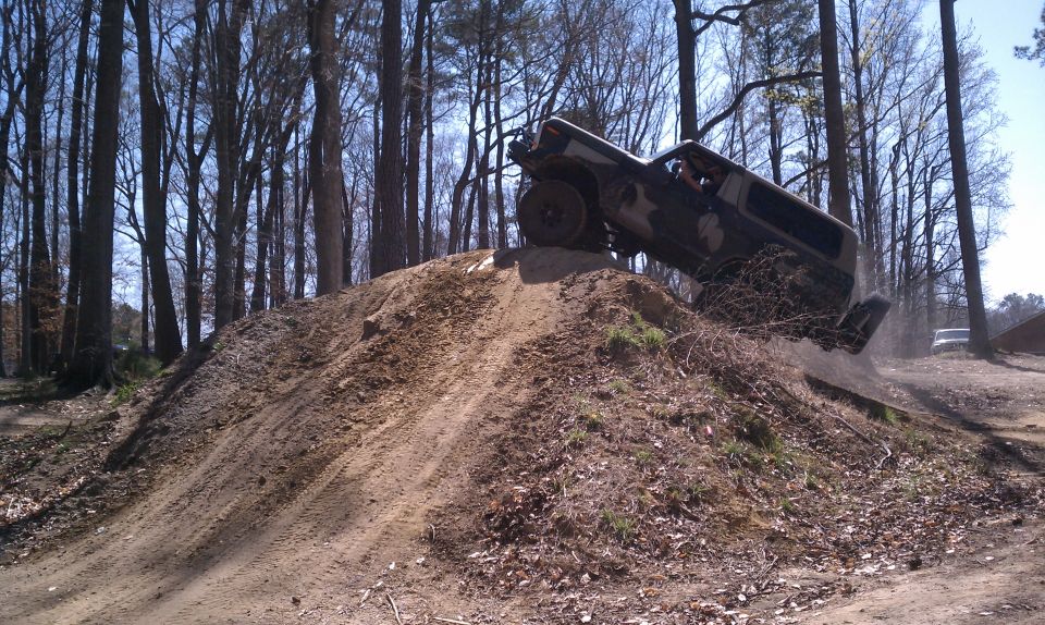off-road vehicle going up a dirt hill in a wooded area