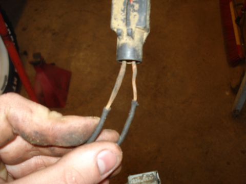 1989 Ford F-250 - Close-up of a dirty electrical connector with frayed wires, held by a hand, with tools visible in the background.