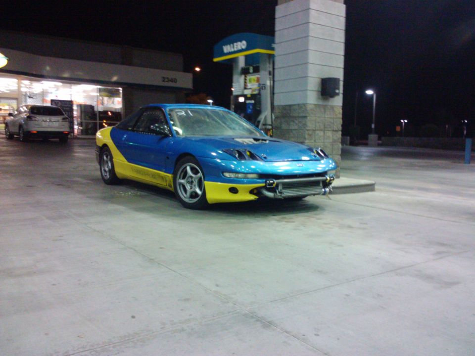 Blue and yellow sports car with aftermarket intercooler at gas station