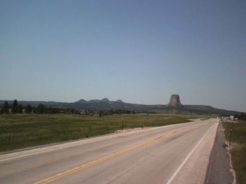 2007 Dodge Caliber - A road stretches towards the iconic Devils Tower formation in a vast, open landscape.