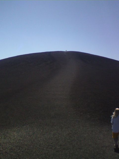 2007 Dodge Caliber - Two people are visible on the summit of a large cinder cone, with another person in the foreground.