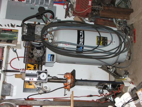 1965 Ford Mustang - A workshop scene with an air compressor and drill press, surrounded by tools and equipment.