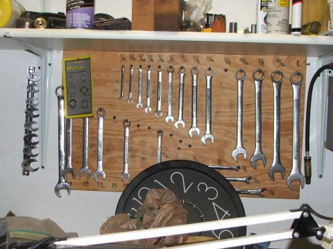 1965 Ford Mustang - A collection of wrenches hangs on a tool board in a garage setting.