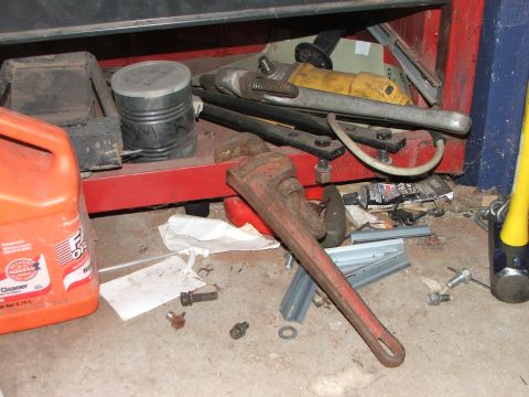 1965 Ford Mustang - A collection of tools and a jug of cleaner are scattered on the floor of a garage.