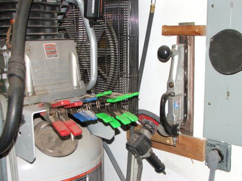 1965 Ford Mustang - Various tools, including an air compressor, clamps, and sander, are organized on a workshop wall.