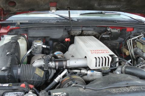 1994 GMC Sierra 3500 - The engine bay features a Turbo Power cover and is visible under the hood of a red vehicle.