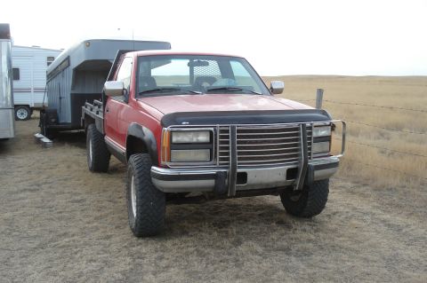 1994 GMC Sierra 3500 - This red GMC pickup truck is equipped with a flatbed and towing a large trailer.