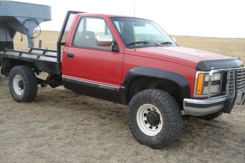 1994 GMC Sierra 3500 - This red 1994 GMC Sierra 3500 pickup features a flatbed conversion and a gooseneck hitch, seen here from a three-quarter front perspective.