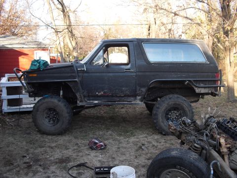 1986 Ford Bronco - This heavily modified SUV sits in a yard, showing off its off-road capabilities and custom modifications.