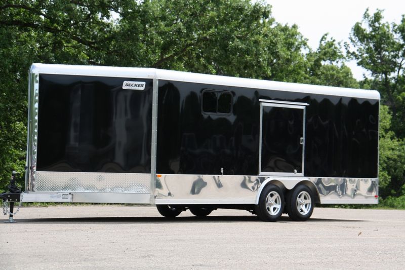Black enclosed cargo trailer with aluminum trim and two windows, parked outdoors