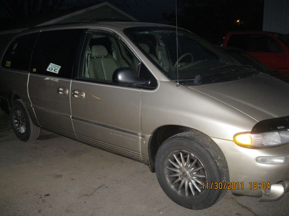 Tan minivan, 3/4 front view. Sticker on driver's door reads 'OC'
