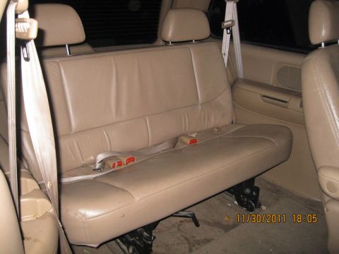 1984 Chevrolet C/K Pickup - The interior of a vehicle shows a tan leather bench seat with seatbelts and headrests.