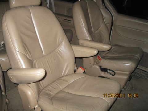 1984 Chevrolet C/K Pickup - Interior view of tan leather captain's chairs with visible seatbelts and armrests.