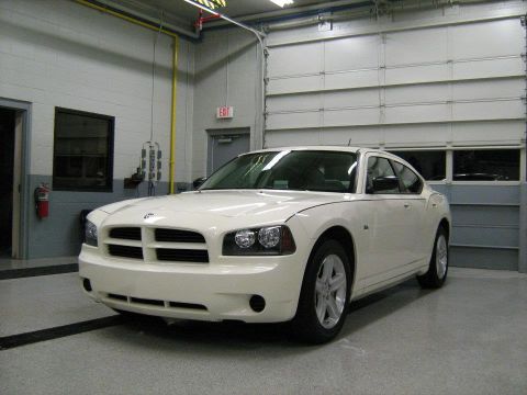1988 Mercury Grand Marquis - A white Dodge Charger is parked inside a garage with large overhead doors in the background.