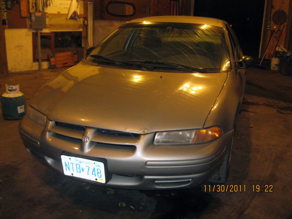 Silver sedan with a dent on the hood, facing forward. License plate NTB 748 is visible