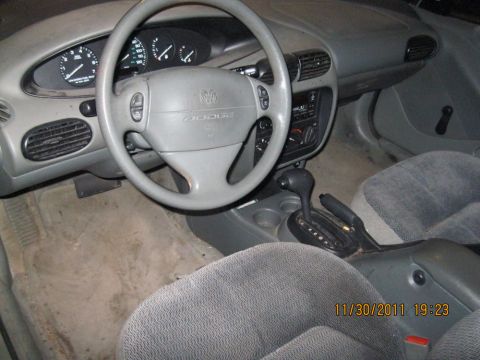 1984 Chevrolet C/K Pickup - The interior of a car, a gray dashboard, steering wheel with a Dodge logo, and an automatic transmission shifter.