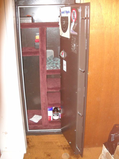 2012 Ford Mustang - An open gun safe is shown with shelves and various items inside, including a target sticker on the interior of the door.