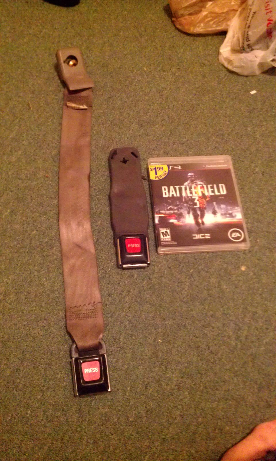Seatbelt assembly and Battlefield 3 video game case on carpet