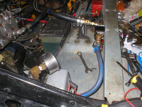 1978 Ford Bronco - Close-up of engine bay components, including hoses, a pressure gauge, and various tools scattered around.