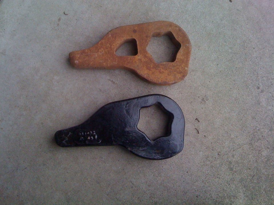 Two torsion bar keys on concrete, one rusty and one black-coated, each with a hex opening