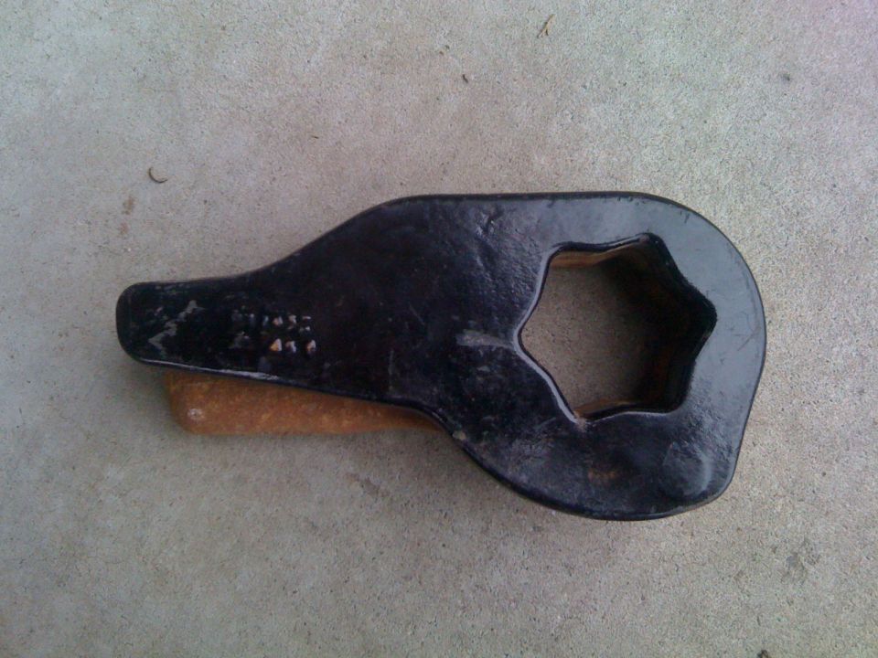 Black torsion bar key with splined star-shaped opening lying on concrete