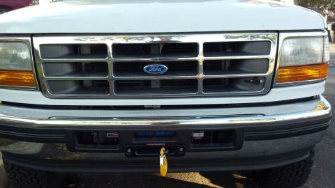 1996 Ford Bronco - The grille and bumper of a white Ford truck are visible, a winch with a yellow tag attached.