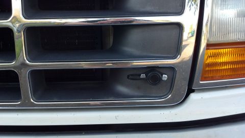 1996 Ford Bronco - Front grille of a white vehicle shows a winch access lever. The grille design suggests a 1992 model year.