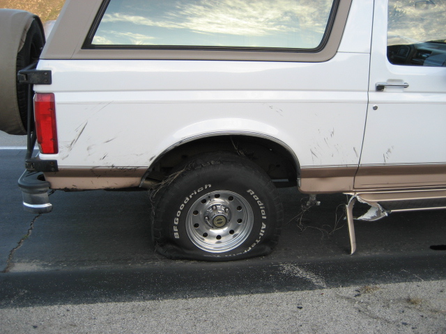 1996 Ford Bronco with a flat rear tire on the driver's side