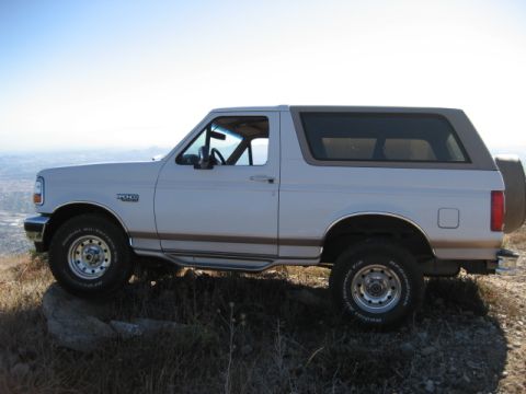 1996 Ford Bronco - This 1996 Ford Bronco is seen from the side, parked on a rocky hill with a distant city view.