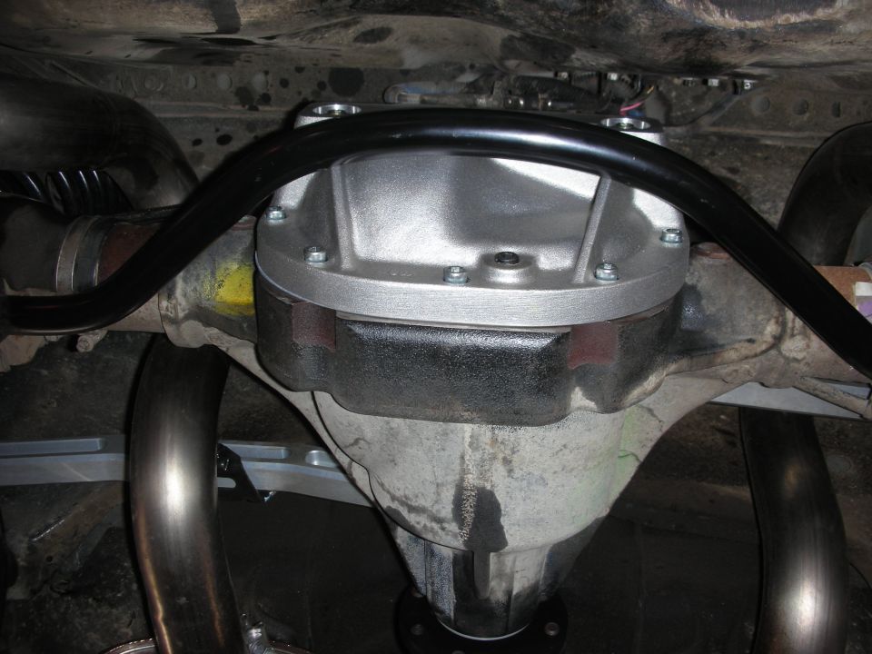 Underside view of a rear differential with a new cover and aftermarket exhaust pipes