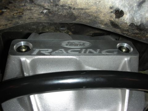 2004 Ford Crown Victoria - A close-up view of a silver Ford Racing engine cover, showing bolted fasteners and a black bar.