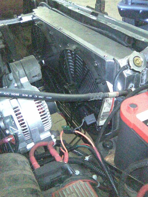 1991 Ford Bronco - Close-up view of engine bay components including a radiator, fan, alternator, and battery with visible hoses and wiring.