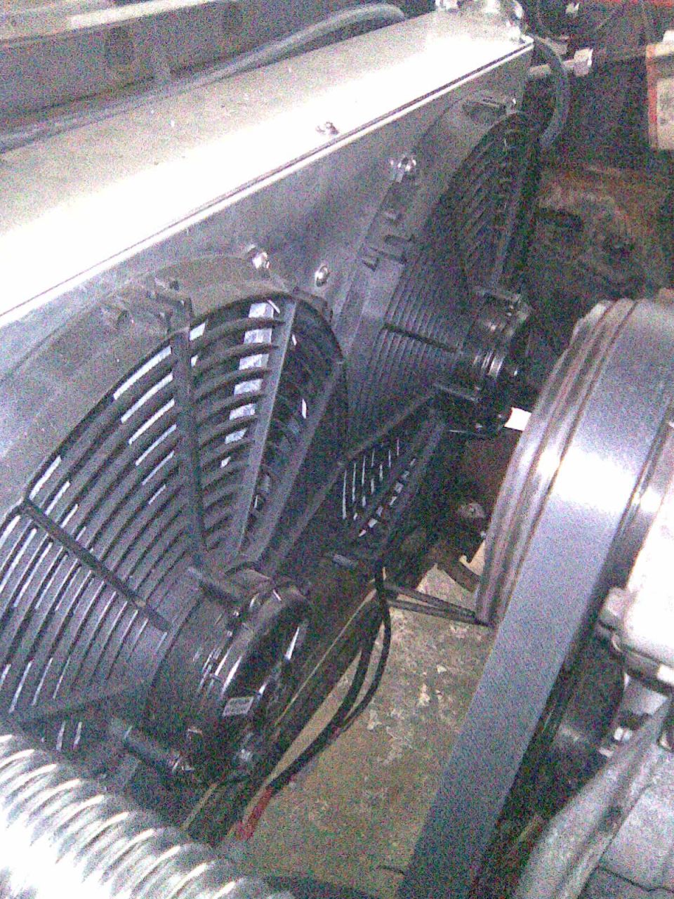 Black electric cooling fan and radiator core in an engine bay with wiring and brackets