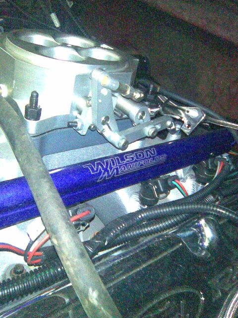 1991 Ford Bronco - Close-up of a polished aluminum Wilson Manifolds intake manifold with a blue-anodized runner section, topped by a four-bore throttle body w…