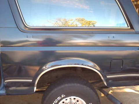 1990 Ford Bronco - Side view of a 1990 Ford Bronco's rear quarter panel, showing body lines and trim.