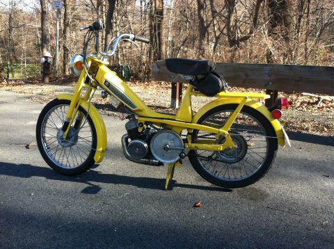 1981 Garelli Rally Sport - Yellow moped parked on asphalt with trees and a wooden bench in the background.