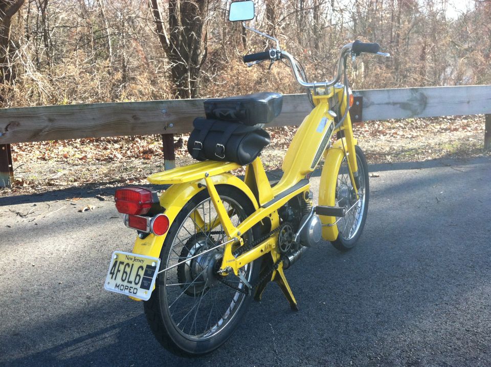 Yellow moped with a black seat bag parked on asphalt, New Jersey plate 4F6L6 MOPED