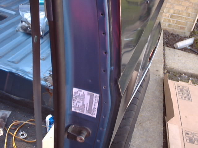 Blue vehicle door jamb with sticker and part of truck bed visible