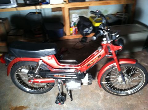 1981 Garelli Rally Sport - This red moped features a black seat and 'Puch Newport II' branding on its side.