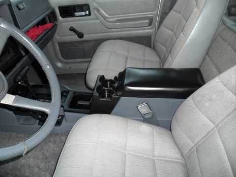 1994 Jeep Cherokee - Interior view of a 1994 Jeep Cherokee, its grey patterned seats and center console with cup holders.