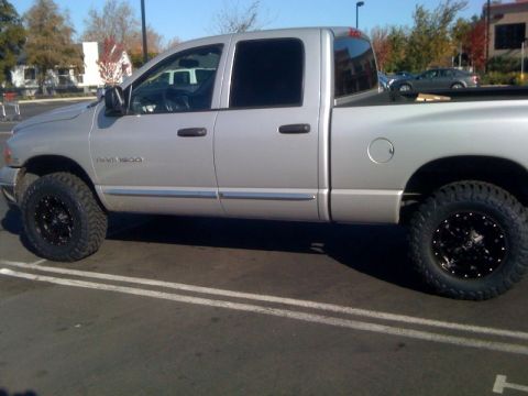 2005 Dodge 1500 - This silver Dodge Ram 1500 pickup truck is shown from the side, custom wheels and tires.