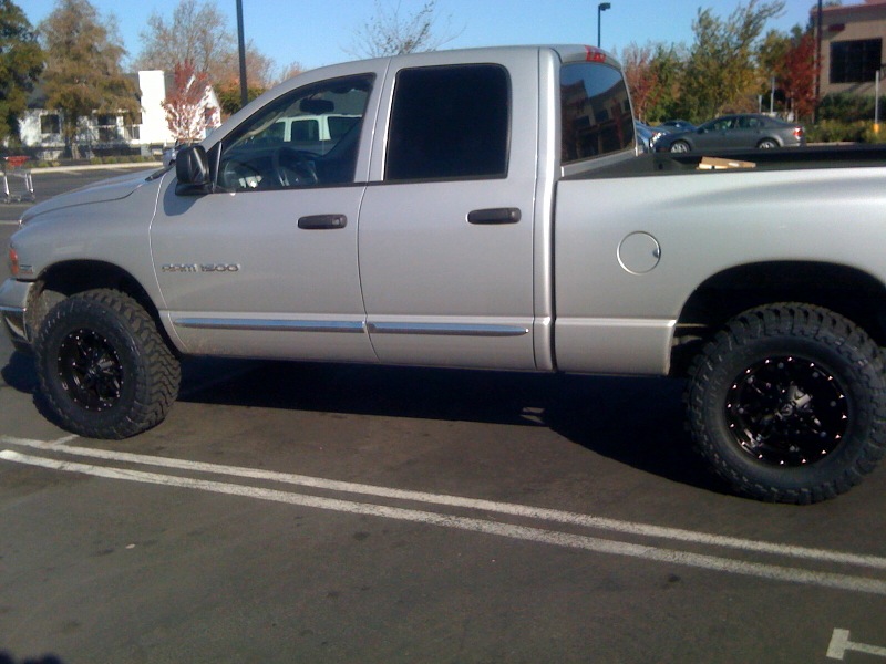 Silver Dodge Ram 1500 pickup truck with aftermarket wheels and tires, parked in a lot