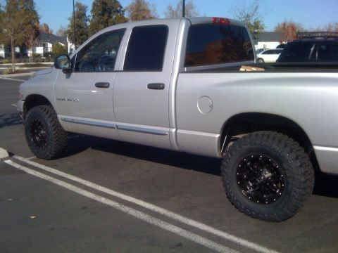 2005 Dodge 1500 - This silver pickup truck has a lifted suspension and aftermarket black rims, suggesting a model year around 2002.