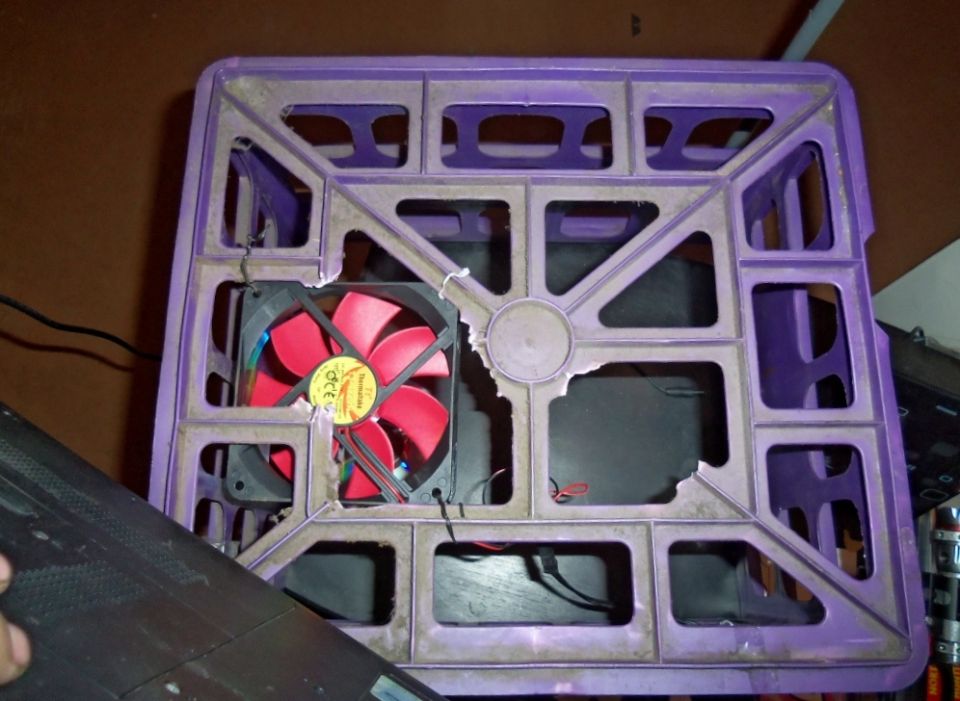 Red computer fan mounted in a broken purple plastic crate