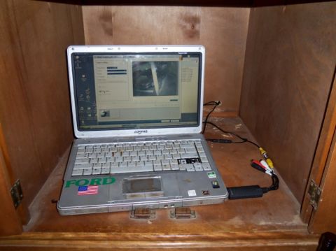 2000 Mercury Grand Marquis - A laptop computer sits on a wooden surface inside a cabinet, displaying a user interface with an image.